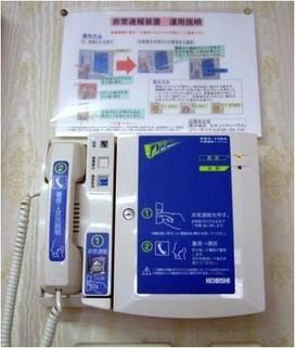 壁に設置された警察直通の非常通報装置。受話器と大きな通報ボタン、操作説明のパネルが写っている。