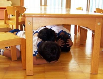 避難訓練で机の下に身を隠す園児ら